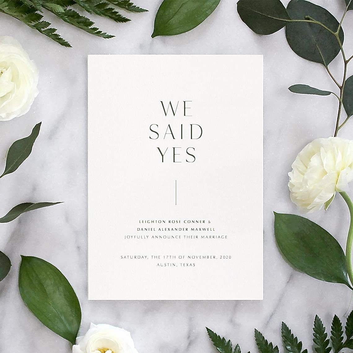 simple 'we said yes' wedding announcement on floral and marble background