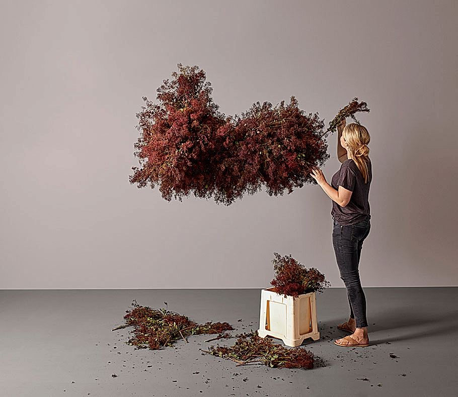 woman adding flowers to a hanging floral installation
