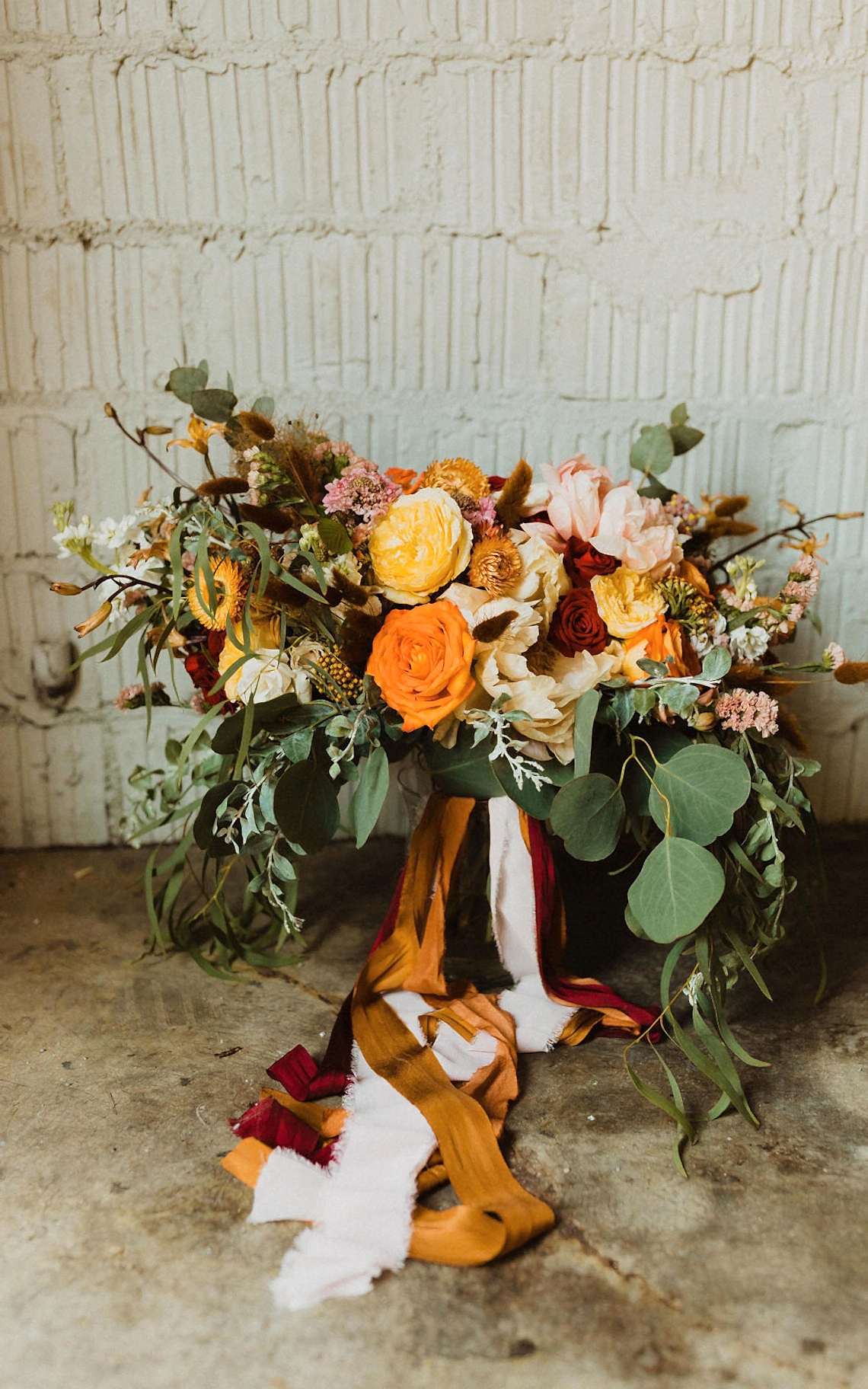 fall wedding bouquet with multiple strands of ribbon hanging from it