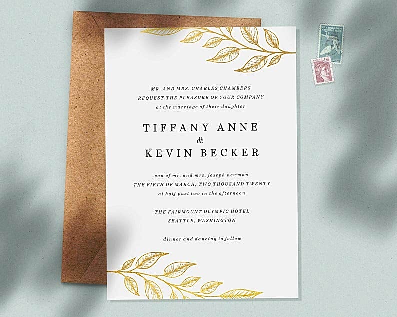 Flat lay image of traditional wedding invitation wording with gold leaf pattern