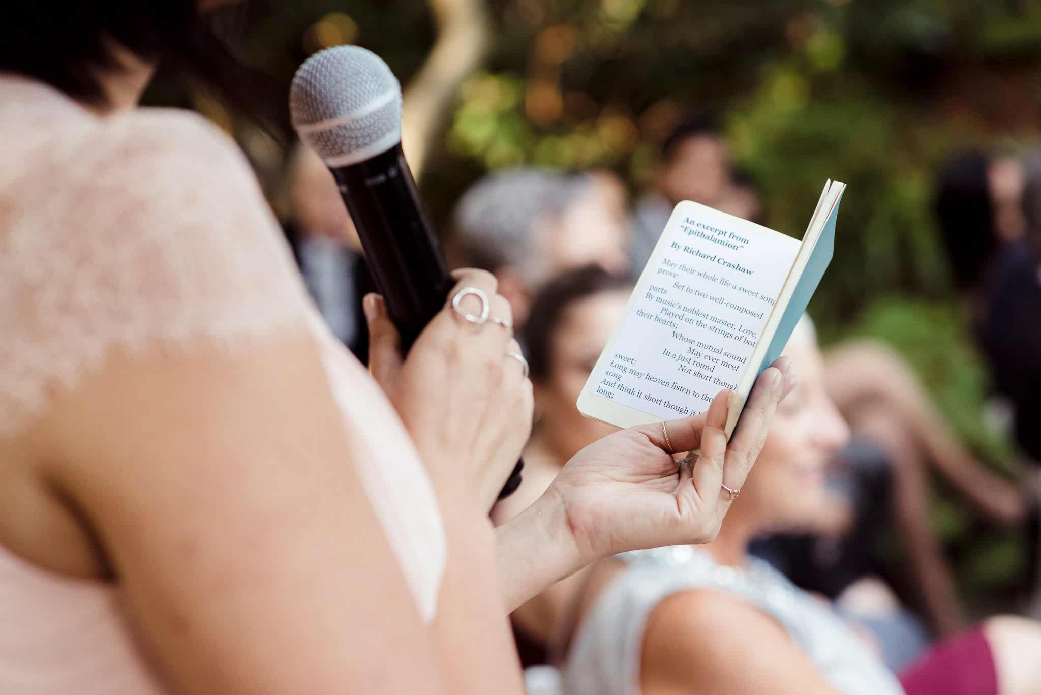 Woman holding microphone and small booklet giving maid of honor speech